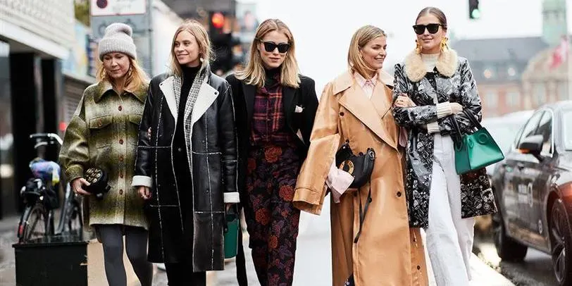 Five stylish women walking on the street, each wearing fashionable winter coats and accessories, showcasing different styles and trends in outerwear.